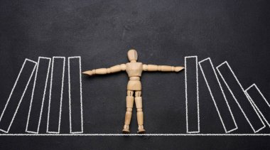Düşen domino taşını tutan tahta kukla. Güçlü kişilik kavramını temsil ediyor.