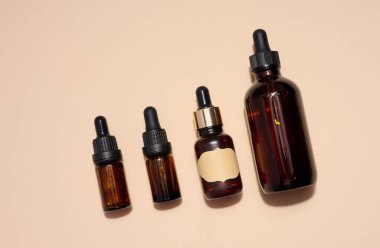 Bej arka planda pipetli kahverengi cam şişe, aromatik yağlar ve kozmetik ürünler için bir kap, üst görünüm.