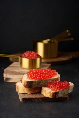 Beyaz buğday dilimli kırmızı havyar siyah masa üstünde ekmek, lüks ve gurme mutfağı kavramı