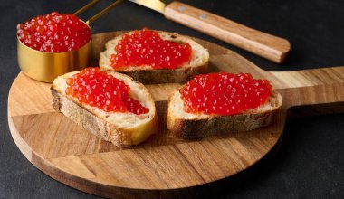 Beyaz buğday dilimli kırmızı havyar siyah masa üstünde ekmek, lüks ve gurme mutfağı kavramı