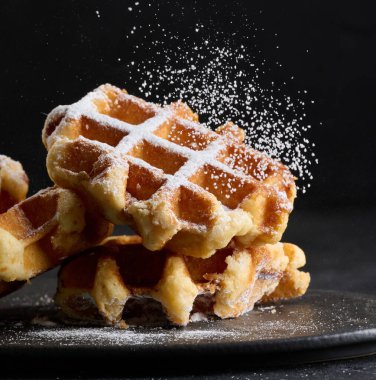 Üzerine pudra şekeri serpiştirilmiş bir yığın Belçika waffle 'ı.