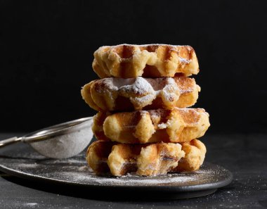 Üzerine pudra şekeri serpiştirilmiş bir yığın Belçika waffle 'ı.