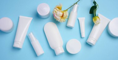 White plastic tubes, jars, and containers for cosmetic products on a blue background, advertising and branding of products