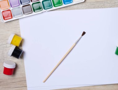 Çizim defterini boş beyaz çarşaflar ve akrilik boyalar ile aç, üst görünüm