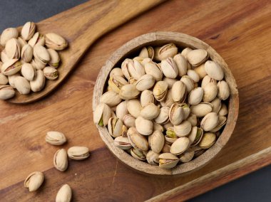 Masanın üzerinde ahşap bir kasede kavrulmuş fıstık.