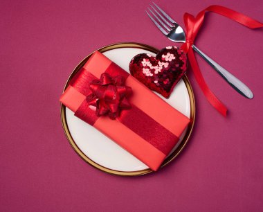 Yuvarlak seramik plaka ve kırmızı zemin üzerinde hediye, üst görünüm