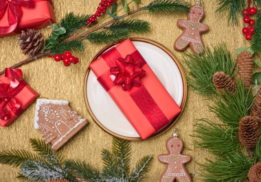 Yuvarlak beyaz tabak ve bej arka planda Noel süsü ile paketlenmiş hediyeler, üst manzara. Neşeli arkaplan