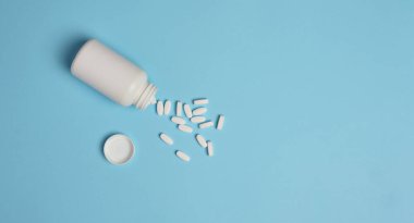 Mavi arka planda beyaz oval tabletler, üst manzara. Boşluğu kopyala