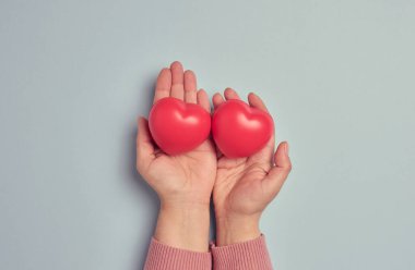 Bir kadının eli, kırmızı kauçuk bir kalbi mavi arka planda tutar, bu da bağış kavramını sembolize eder.