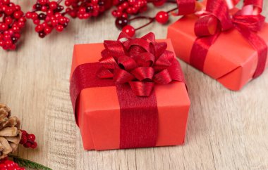 Kırmızı kağıda sarılı bir hediye kutusu ve masanın üstünde bir fiyonk.