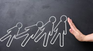 Bir kadın el tahtaya tebeşirle çizilmiş figürleri destekler, güçlü liderlik ve yardım kavramını sembolize eder..