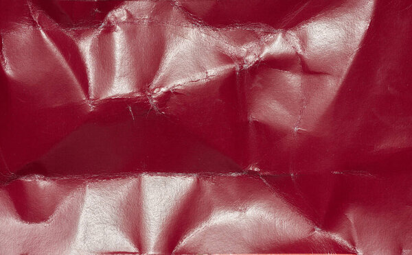 Crumpled red cardboard with creases, full frame