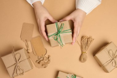 Bej arka planda hediye kutusunu tutan kadın eller. Yukarıdan görüntüle
