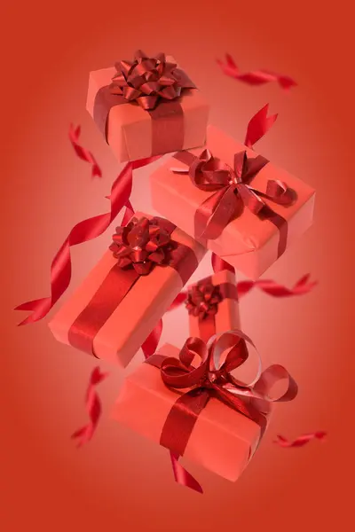 Red boxes with gifts levitate on a red background with silk ribbons