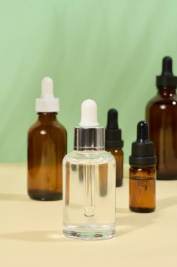 Kozmetik ürünleri için cam şişeler, bej arka planda pipetli yağlar.
