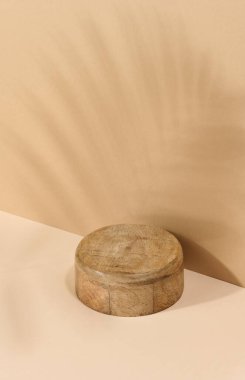 Yuvarlak ahşap platform, kahverengi arka planda bir palmiye yaprağının gölgesi. Kozmetik gösterimi için yer