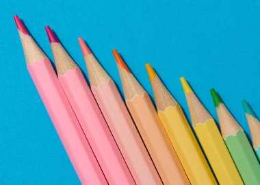 Mavi arka planda çok renkli ahşap kalemler, üst manzara.