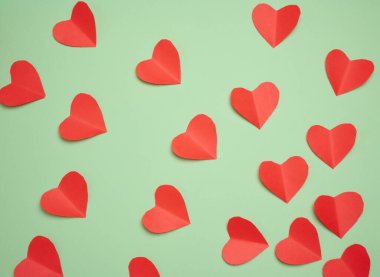 Yeşil zemin üzerinde kırmızı kağıt kalpler, üst görünüm