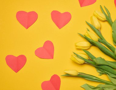 Sarı arka planda yeşil yapraklı, çiçek açan sarı laleler.