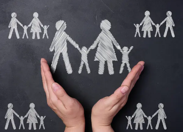 Chalk drawn family on a black board and two female hands, concept of love and support
