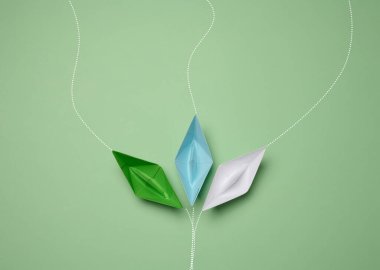 Paper boats on a green background with paths of movement, representing the concept of individuality. Top view clipart