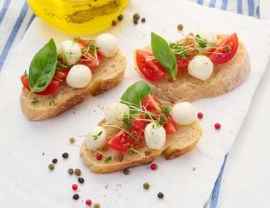 Yuvarlak mozzarella, kiraz domatesleri ve bir parça beyaz ekmek üzerine mikroyeşiller, sağlıklı bir sandviç.