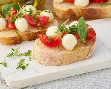 Yuvarlak mozzarella, kiraz domatesleri ve bir parça beyaz ekmeğin üzerine mikroyeşiller.