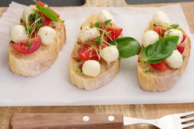 Yuvarlak mozzarella, kiraz domatesleri ve bir parça beyaz ekmek üzerine mikroyeşiller, sağlıklı bir sandviç.