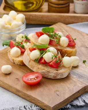 Yuvarlak mozzarella, kiraz domatesleri ve bir parça beyaz ekmek üzerine mikroyeşiller, sağlıklı bir sandviç.