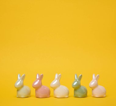 Sarı arka planda seramik dekoratif tavşanlar, bayramlık Paskalya arkaplanı