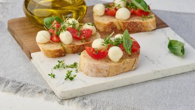 Yuvarlak mozzarella, kiraz domatesleri ve bir parça beyaz ekmeğin üstünde mikroyeşiller.
