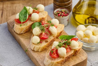 Yuvarlak mozzarella, kiraz domatesleri ve bir parça beyaz ekmek üzerine mikroyeşiller, sağlıklı bir sandviç.