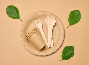 Kağıt bardaklar, tahta kaşıklar ve çatallar bej arka planda, üst manzara