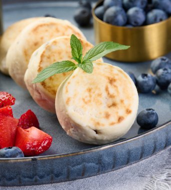 Mavi tabakta böğürtlenli küçük kızarmış peynirli kek. Sağlıklı kahvaltı.