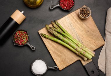 Siyah ahşap arka planda taze yeşil kuşkonmaz filizleri. Yukarıdan görüntüle