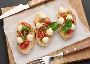 Yuvarlak mozzarella, kiraz domatesleri ve bir parça beyaz ekmek üzerine mikroyeşiller, sağlıklı bir sandviç.