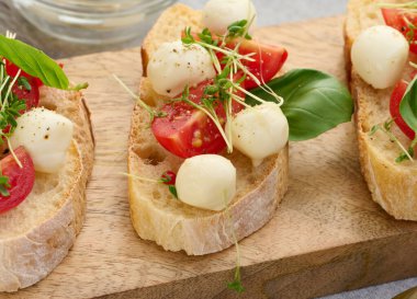 Yuvarlak mozzarella, kiraz domatesleri ve bir parça beyaz ekmek üzerine mikroyeşiller, sağlıklı bir sandviç.