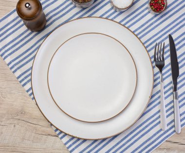 Yuvarlak beyaz seramik tabak, bıçak ve çatal masanın üstünde, üst manzara