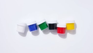 Plastik kavanozlar, beyaz arka planda çok renkli guaj, üst görünümde.