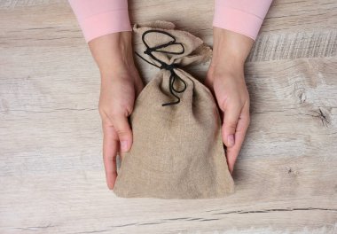 Doldurulmuş bir bez torba tutan kadın eller, zenginlik ve başarı kavramı