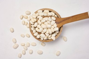 Beyaz masada beyaz bir tabakta çiğ fasulye..