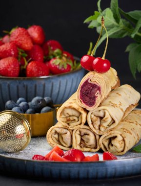 Bir yığın halinde krepler, biri kesilmiş ve böğürtlen dolgulu, yakın