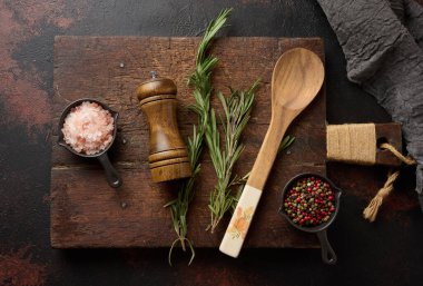 Mutfak gereçleri ve Himalaya tuzu, renkli biberler, taze biberiye ve ahşap baharat öğütücüsü de dahil olmak üzere baharatlı mutfak malzemeleri. Üst görünüm