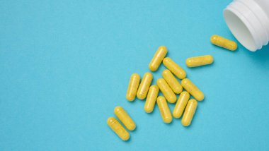 Mavi arka planda kapsüldeki sarı haplar, ağrı kesici.