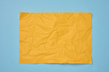 Mavi arka planda buruşuk dikdörtgen sarı kağıt, üst manzara. Yazı için yer