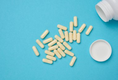 Oval white capsules on a blue background. Medical pills, top view
