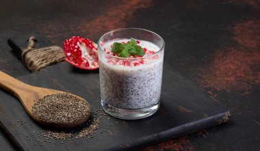 Bir bardak chia tohumu ve yoğurt, masada nar.