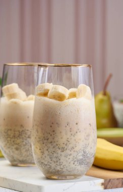 Beyaz masada taze muz dilimleriyle süslenmiş Chia ve yoğurt tatlısı.