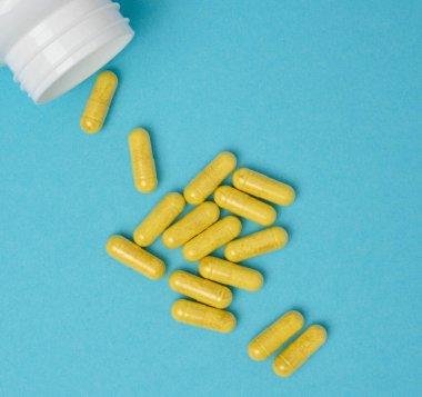 Mavi arka planda kapsüldeki sarı haplar, ağrı kesici.