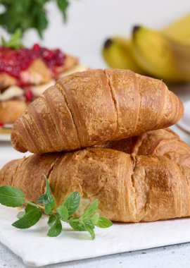 Pişmiş kruvasan ve beyaz bir masada bir tutam nane, kahvaltı.